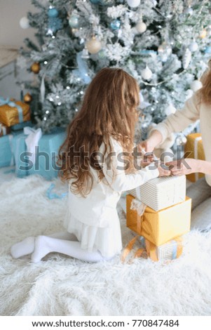 mother and daughter under the Christmas tree opening gifts