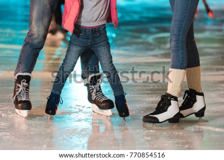 cropped shot of young family in skates skating together on rink