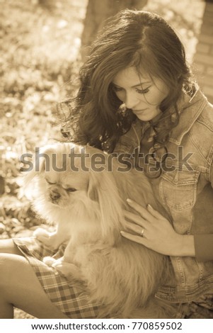 Senior dog owner girl play with pet in park outdoor, brunette girl kiss little puppy.Domestic canine pekingese.Young woman cuddling her doggy. Dog lover play with happy her dog in park