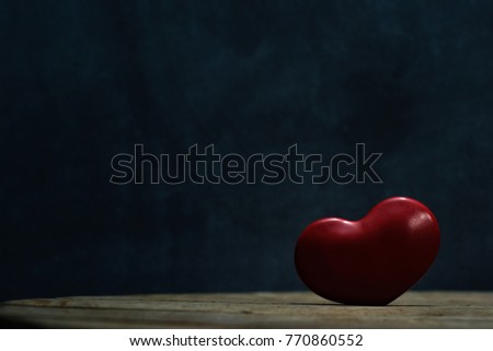Red heart symbol of love on a round wooden table. Beautiful dark background.