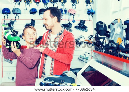 Smiling father and son examining various a roller-skates at the sports store. Focus on both persons