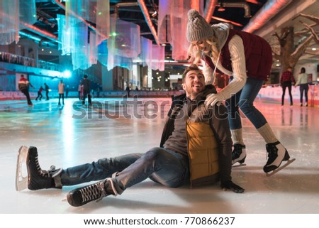 beautiful smiling young couple teaching ice skating on rink