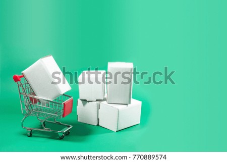 White box with shopping trolley on isolated green