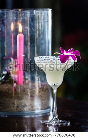 Composition with margarita cocktail, orchid flower and burning candle on the blurred background