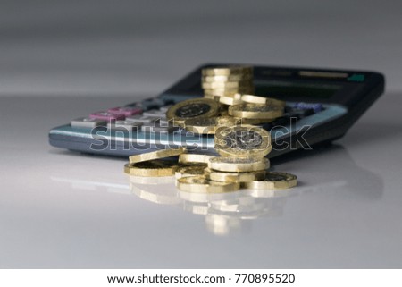 Pound Coins with Calculator - Grey Reflective Background Royalty-Free Stock Photo #770895520
