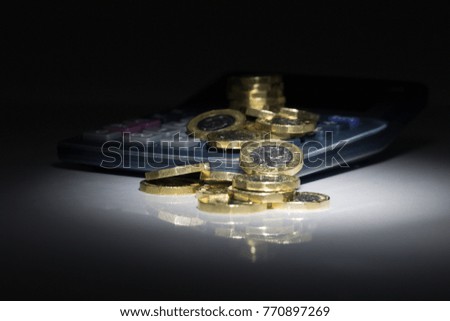 Pound Coins with Calculator - Black Reflective Background Royalty-Free Stock Photo #770897269