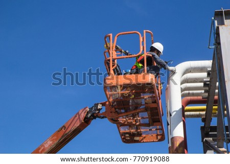 Male workers in a boom lift of thickness pipeline oil inspection.