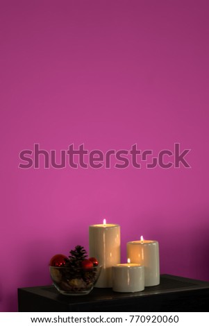 New year decoration with candlelight and winter ornaments on magenta bacground
