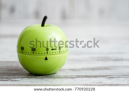 Green kitchen cooking timer with apple shape on white wooden background