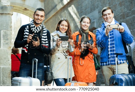 Group of happy friends walking through street with camera and smartphone 