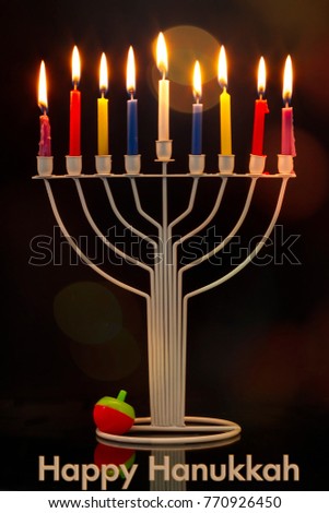 Happy Hanukkah jewish holiday. Menorah traditional candelabra with burning candles and Hanukkah Dreidel Sevivon against black background
