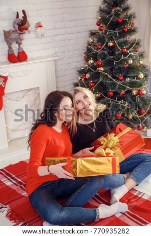 Christmas feeling. After Christmas party. Girls with happy faces near Christmas tree on wooden wall background.