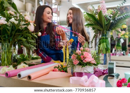 Workplace at the flower shop. Beautiful composition of roses, lupines and grass, rolls of decorative paper and ribbons. Presents for beloved ones.