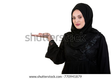 studio shot of young woman wearing traditional arabic clothing. she's holding her hand to the side Royalty-Free Stock Photo #770941879