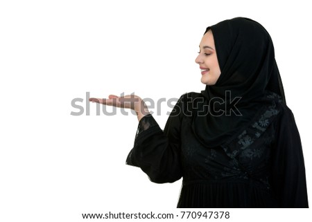 studio shot of young woman wearing traditional arabic clothing. she's holding her hand to the side Royalty-Free Stock Photo #770947378