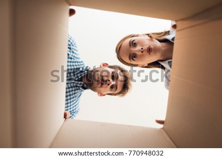 The girl and the boy are looking at the empty box. View from inside the box close-up.