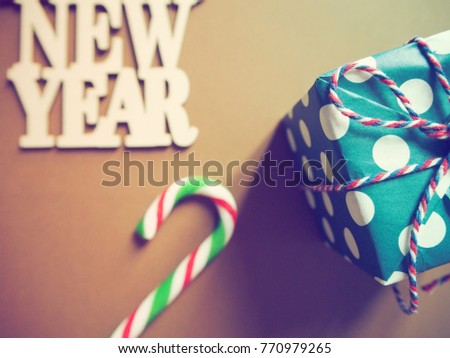 Brown NEW YEAR background with green red white candy cane and a gift box. Concept image for special days in New Year 2018. (Top view, selective focus, vintage filter effect)
