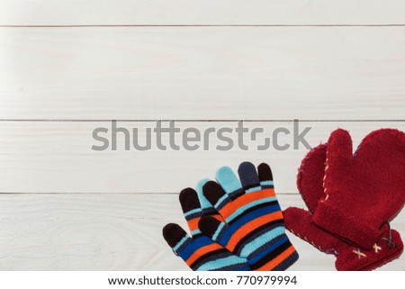 Winter children's mittens lie on a wooden background
