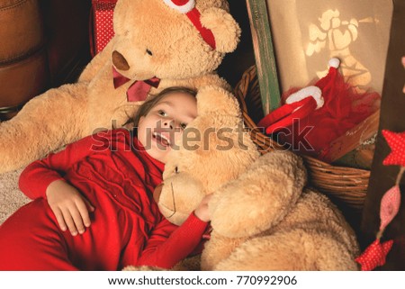 A little girl play with christmas toys in home interior. Child smiles and laughs.