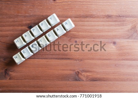 Happy new year card concept. Holiday technology concept. Flat lay view from above on the table with computer keyboard keys buttons on a wooden background.