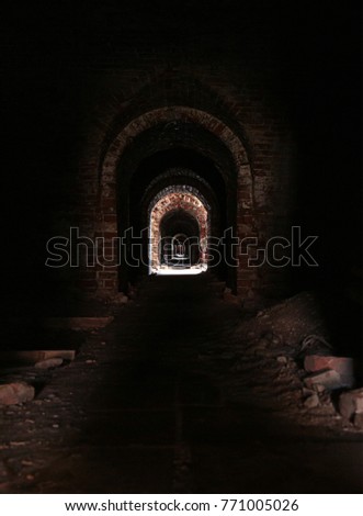 uninhabited horror horrible long corridor dark with a distant bright light, eerie catacombs with ruinous walls