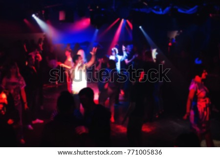 blurred people dancing on the dance floor at a night club concert