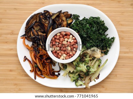 High Quality picture of Roasted Egg plant, Broccoli, Kale, Yellow Bell pepper ,Fennel bulb, Peanuts arranged in a plate, top view