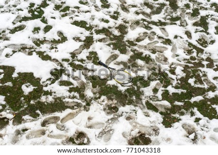 Tennis racket in a snowy field, winter time, footsteps around
