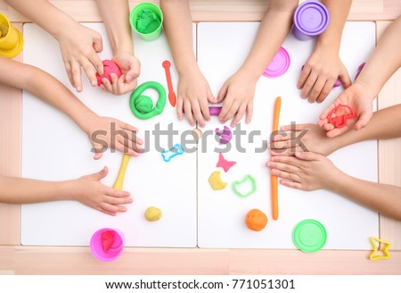 Little children engaged in playdough modeling at table, top view