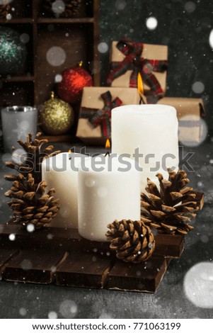 Burning candles and Christmas attributes on a dark background. Snow