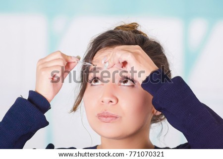Close up of young beautiful woman doing a mess in her eyebrow in a blurred background Royalty-Free Stock Photo #771070321