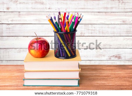 Books and an apple on a wooden table