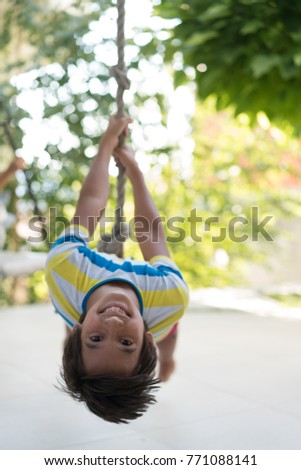 Cute happy little boy upside down on swing rope Royalty-Free Stock Photo #771088141