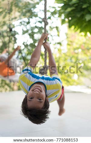 Cute happy little boy upside down on swing rope Royalty-Free Stock Photo #771088153