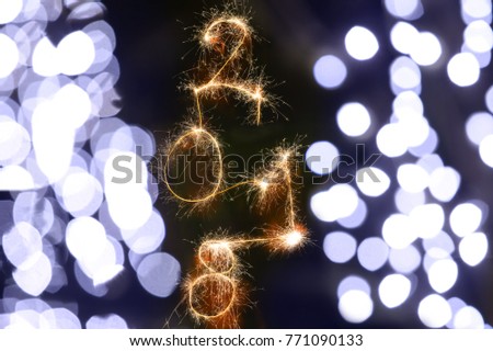 Isolated 2018 written with Sparkle firework on black background with blurred decoration lights, happy new year 2018 concept.