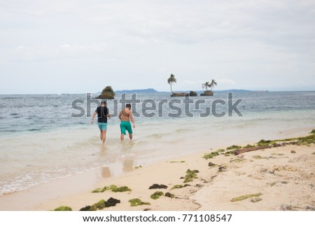 Two teenagers in snorkelling gear walking into the ocean