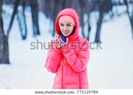 young woman in warm clothes with cup in winter forest .happiness, winter holidays, christmas,