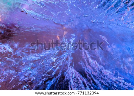 frozen ice wall with illuminated texture by blue and purple light in background