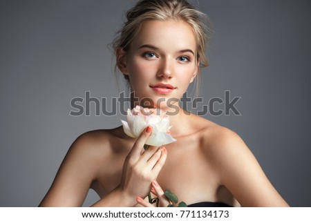 Young beautiful lady with rose on grey background. Skin care concept