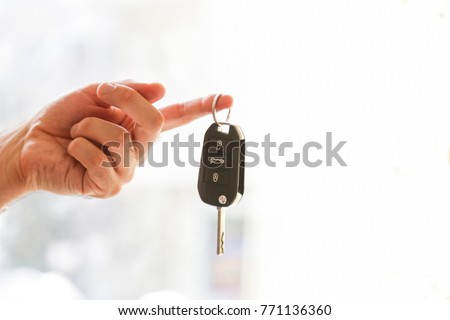 Hand with a car key. Isolated on white background. Royalty-Free Stock Photo #771136360