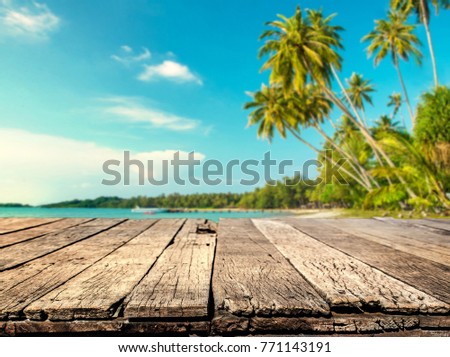 Wood table with blurred sea and coconut tree background