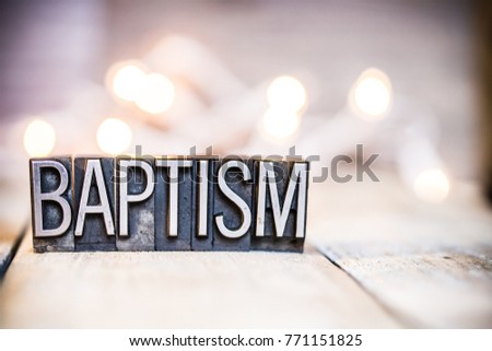 The word BAPTISM written in vintage metal letterpress type on a bokeh light and wooden background.