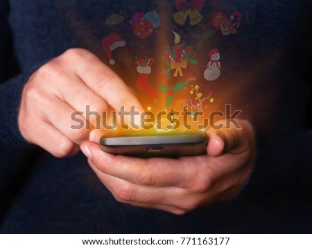 Woman hands holding and using smartphone mobile or cell phone for Christmas or xmas. Concept for celebration with logos of  Santa Claus hat, a holy berry, a snowman, a gingerbread, a candle and bells