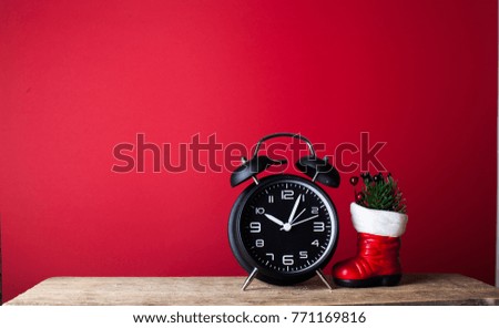 Alarm clock with santa claus shoes on red wood over white rustic background with copy space for text