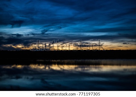 Awe inspiring blue and gold sunset clouds and trees reflected in water at the Quabbin Reservoir in Massachusetts USA Royalty-Free Stock Photo #771197305
