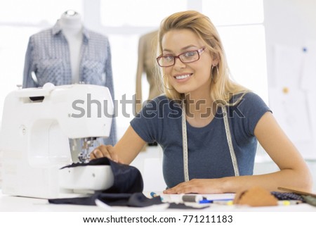 Attractive young woman fashion designer smiling to the camera proudly working at her atelier using sewing machine putting together new garments copyspace achievement small business owner creativity
