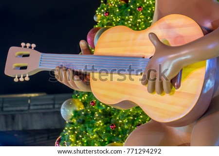 Close-up Cartoon play guitar with Christmas tree in background.