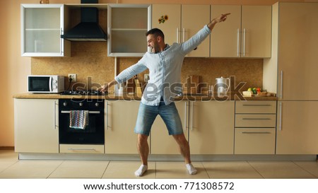 Handsome young funny man dancing in kitchen at home in the morning and have fun on holidays