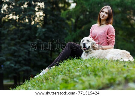 Photo from below of brunette sitting with dog on green lawn