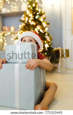 New Year picture of boy in Santa cap with gift box on background